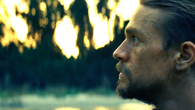 Charlie Hunnam (as Percy Fawcett) looking out over a verdant green background. This is a still from the film the Lost CIty of Z