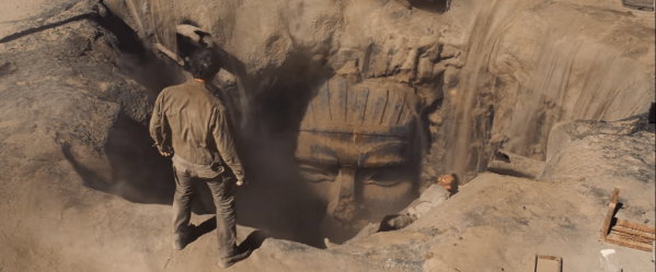 Looking down at a tomb mouth open in the sand. This is a still from the film The Mummy