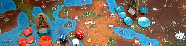 A board game laid out, showing a desert like biome surrounded by water, three dice and cardboard figures above other tokens. This is the play space for the board game Tales of the arabian Nights.