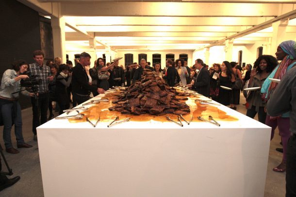 A pile of food rests in the middle of a table, tongs laid out nearby.