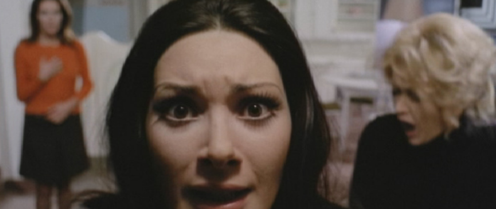 A brunette woman looks at the camera, gaze panicked.