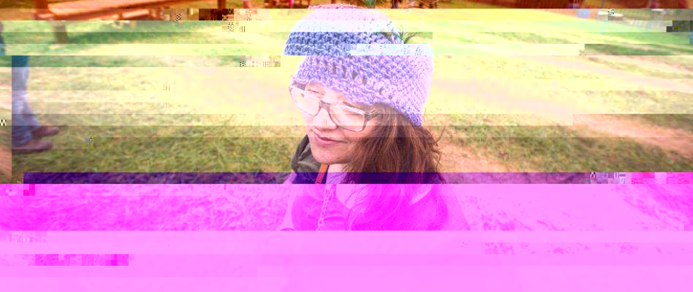 the writer, wearing a purple knit cap, hair long and grass green behind her.