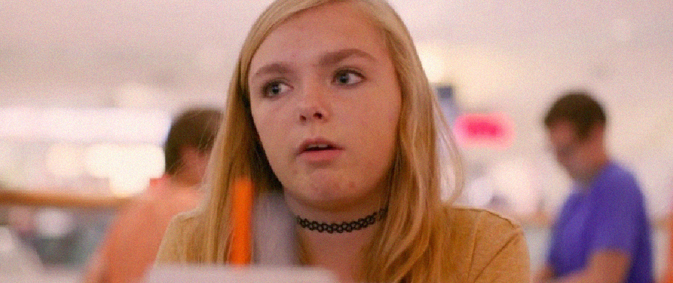 A blonde girl in a choker, looks out confusedly, a straw and cup resting in front of her. This is a still from the film Eighth Grade
