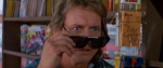 a scene from They Live of Roddy Piper with his sunglasses tilted down on his nose