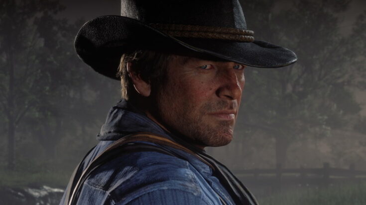 A man in a denim shirt and dark cowboy hat squints at the viewer.