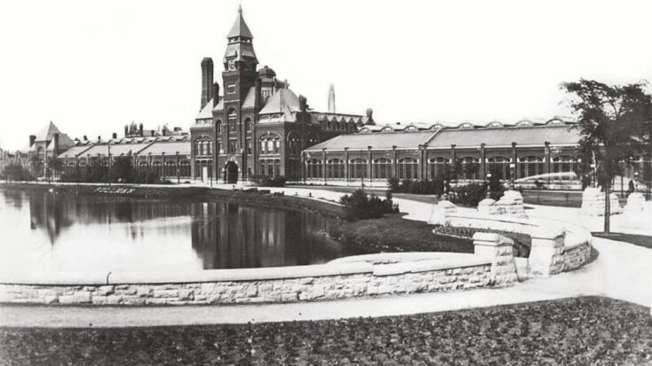 An old, black and white photo of a stately municipal building rising above a large reflecting pool.