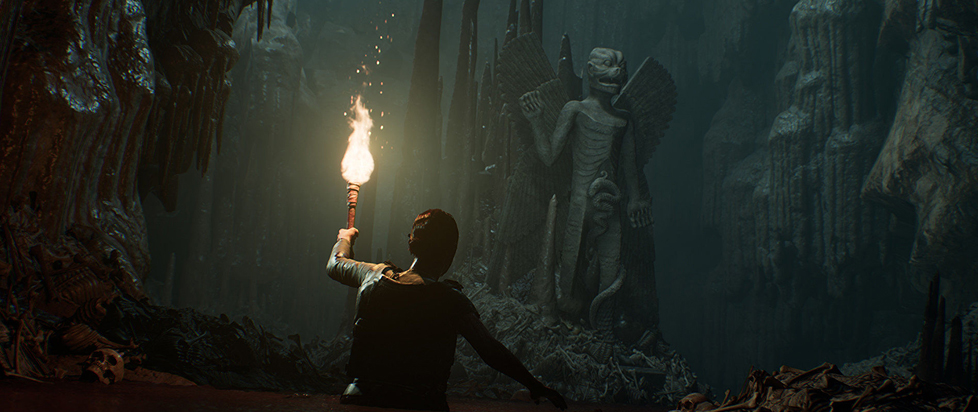Ad adventurer wearing a leather backpack holds a torch aloft in a subterranean cave, illuminating an eerie winged statue with the body of a human and the head of a large predator cat.