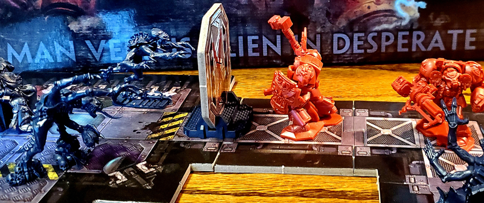 figures from the game Space Hulk, blue and red, moving across a tabletop.