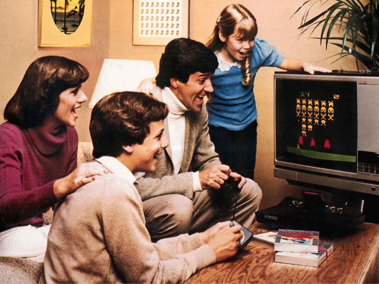 A 1980s family crowds around a television set playing an Atari game.