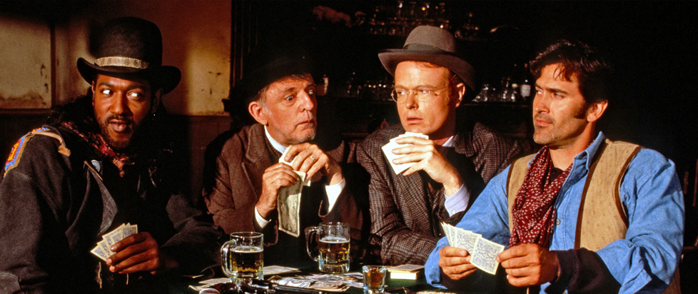 Four Old West men sit at a poker table, eyeing each other suspiciously.