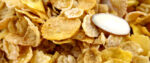 A close-up on a bowl of cornflakes. A single slivered almond features prominently.