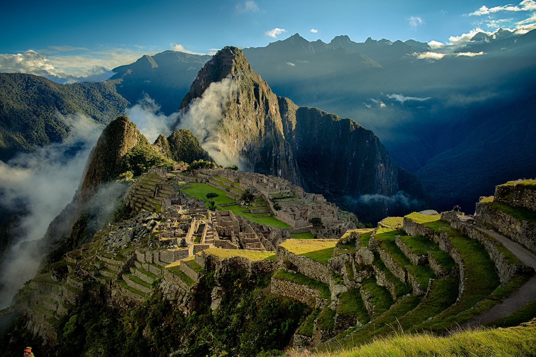 An aerial view of the citadel of Machu Picchu. Huyana Picchu rises above the clouds just beyond.