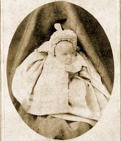 A sepia photograph of an infant in a white christening dress and bonnet, said to be Edith Rockefeller