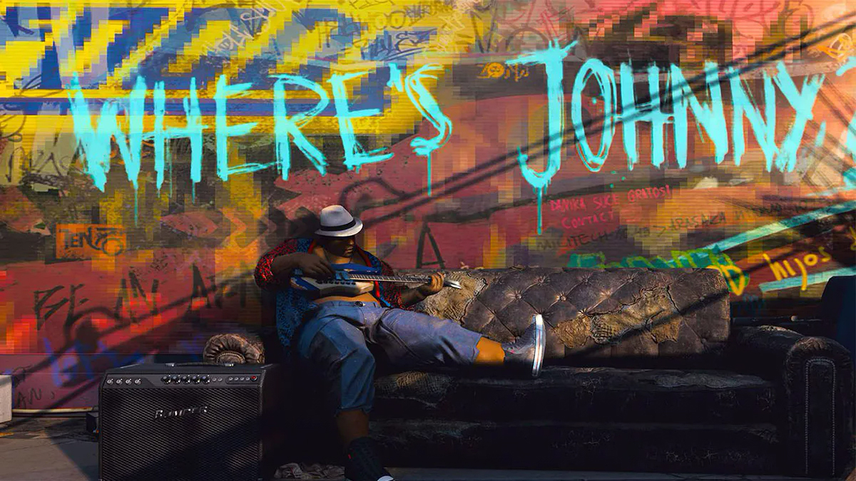 A man sits splayed on an abandoned sofa tooling around on an electric guitar. The words "Where's Johnny" are painted on the graffiti-covered wall behind him.