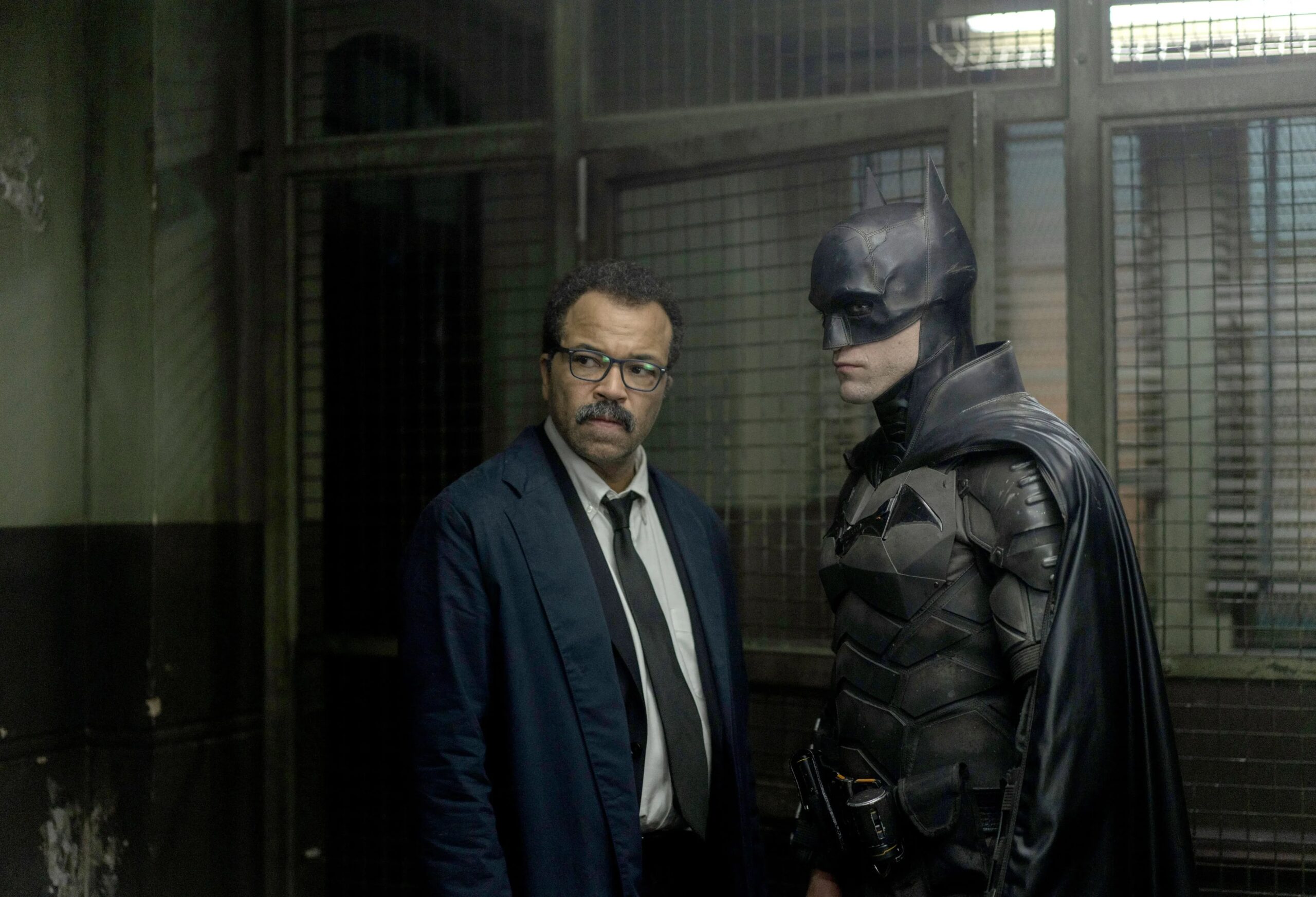 In a still from The Batman, Commissioner Jim Gordon and Batman stand together in a dingy Gotham City police station.