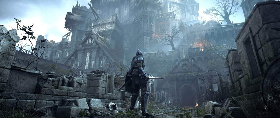 In a screenshot from Demon's Souls, a beleaguered knight stands in the ruined courtyard of a great grey cathedral.