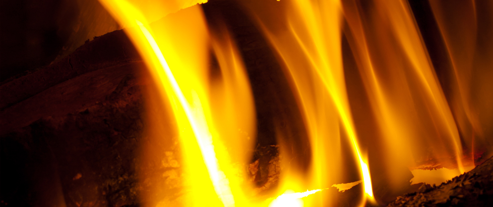 A close-up photo of a log burning in a roaring fire, the flames like yellow liquid.