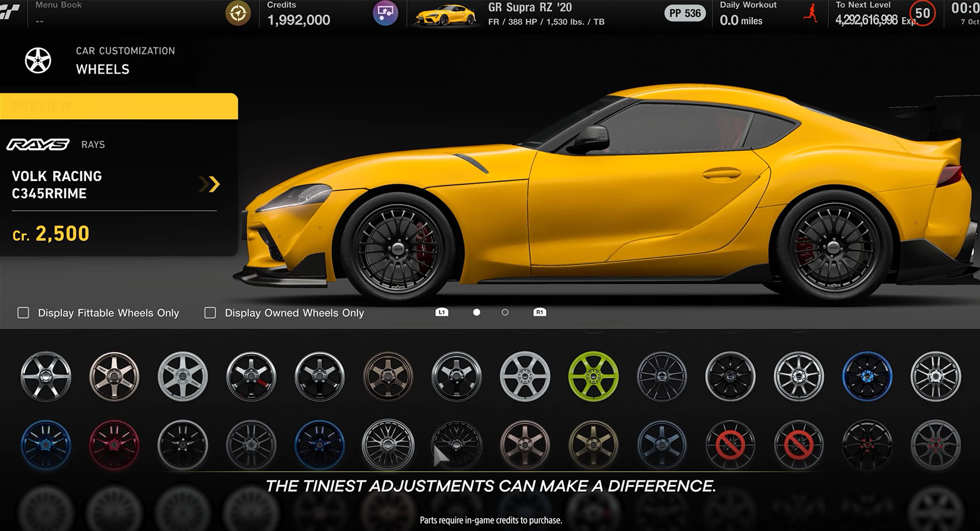 In the car customization screen of Gran Turismo 7, several hubcap styles are displayed beneath a sleek yellow race car. The bottom of the image reads "The tiniest adjustments can make a difference."