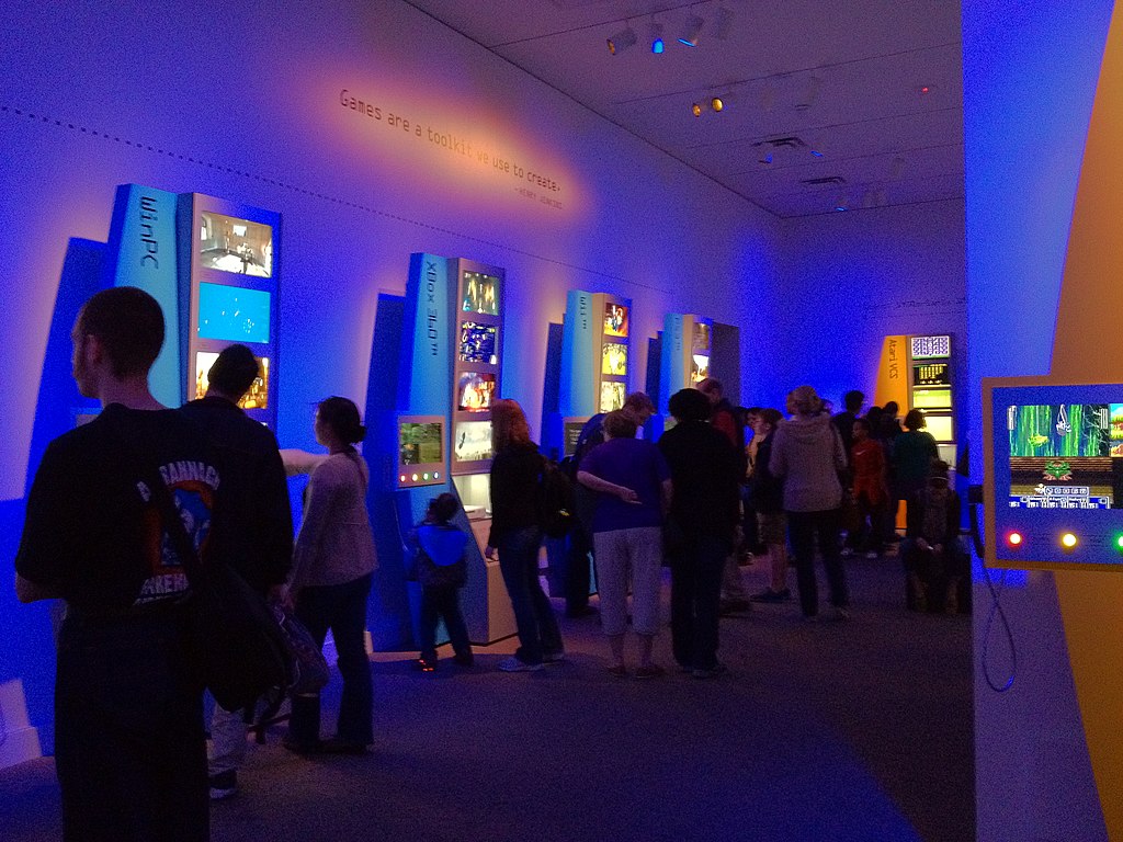 Several people mill about a videogame exhibit in a museum.