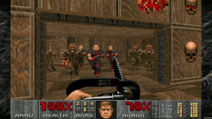 In a first-person perspective from the videogame DOOM, the protagonist holds a chainsaw in front of himself as enemies flood through a stone archway.