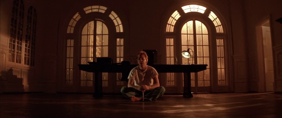 Keifer Sutherland is sidding criss-cross-apple-sauce in a room with high arched windows and afternoon yellow light with a lone lamp for company