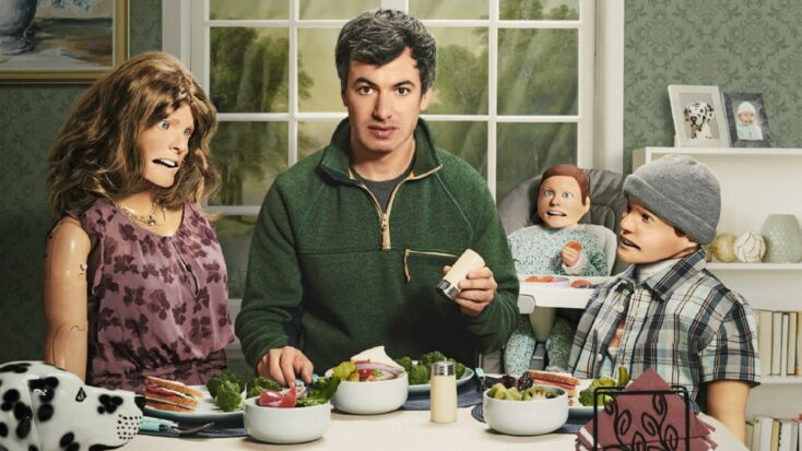 In a promotional shot from The Rehearsal, Nathan Fielder sits at a kitchen table surrounded by a family made up of dummies.