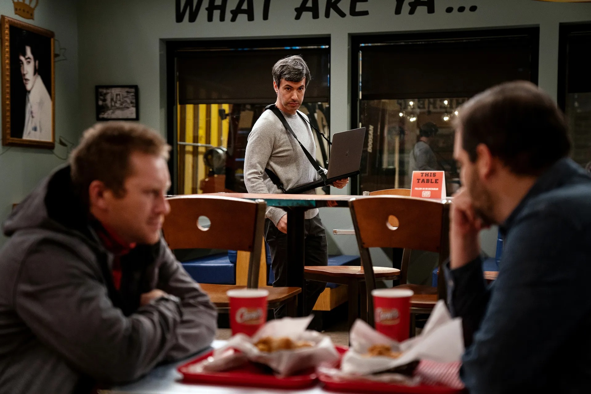 In a shot from The Rehearsal, Nathan Fielder, a laptop strapped to his chest, observes two men having a conversation across a table at a diner.