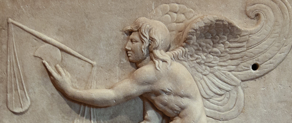 A stone frieze depicting a winged figure holding unbalanced scales.