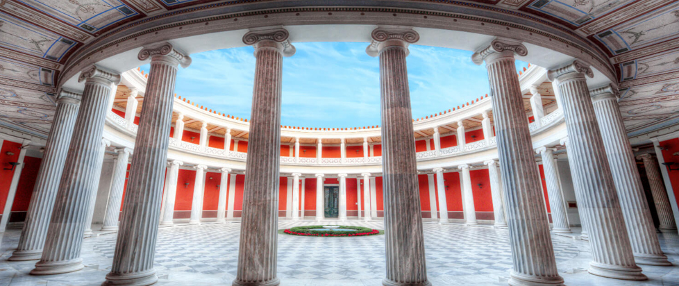 A photograph taken inside the courtyard of a Neoclassical building. The red and white color scheme and angle of the photo give the viewer a feeling akin to being inside of a monster's locked jaw, peering out through its teeth.