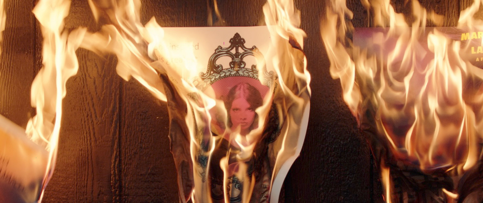 Promotional image for Immortality, with a print of a woman in fancy frame writhing in flames