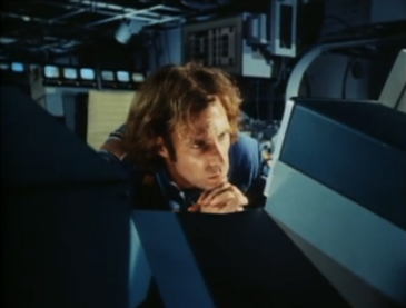 Bruce Dern looking very contemplatively at a big boxy monitor, with rows more flashing behind him, and a space HVAC unit above