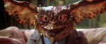 A close-up of the gremlin Brain from Gremlins 2. He looks a bit more intelligent than his brethren due to the wire-rimmed glasses magnifying his yellow-red eyes.