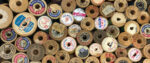 A top-down view of several thread spools, most with colorful labels on top.