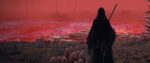 A cloaked figure holding a sword gazes across a barren landscape of red fog and blackened soil.