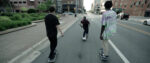 Three boys skateboard down a New York street.