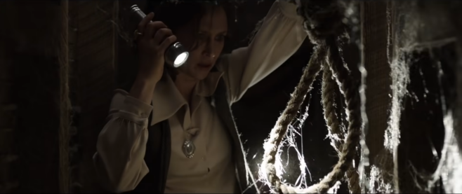 Another screenshot from the trailer for The Conjuring, where one of the paranormal investigators finds a noose and is looking at it with great suspicion