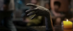 Screenshot from Talk to Me, featuring the mummified medium's hand gracefully reaching out as if to be shaken with a lone candle in the background