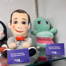 Plushies of Pee-wee and Chairry sit together on a glass display shelf at the Kidrobot booth at New York Comic Con.