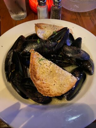 A bowl of mussels piled high accompanied by heels of crusty bread to soak up the broth.