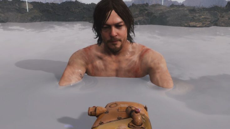 Death Stranding's Sam relaxes in a hot spring, his precious cargo floating in the water before him.