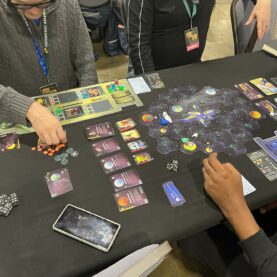 Table-view of several players playing the colorful and complex card game Stardriven.