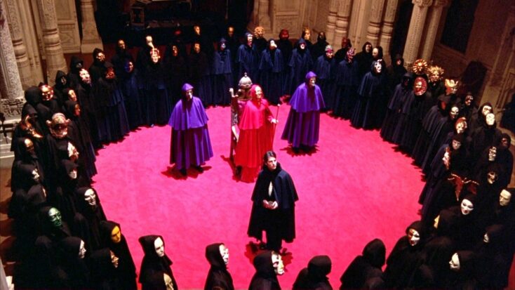 Masked and robed onlookers observe a ritualistic ceremony in a scene from Kubrick's Eyes Wide Shut.