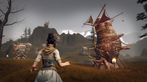 a person in a scarf and dress and ponytail stands in a field with a few man made cocoon type structures off in the gloomy distance