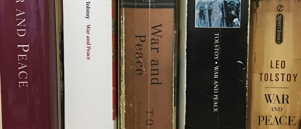 Several paperback versions of War and Peace neatly lined up on a bookshelf.