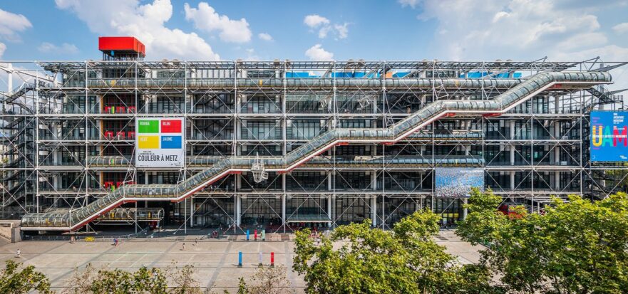 An outside view of the Centre Pompidou showing the inside-out style of the building's exposed beams and staircases.
