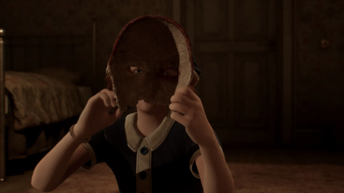 A screenshot from Alone in the Dark where a child is holding up a papier-mache mask and looking through the eye hole into the camera to stare directly at the viewer 