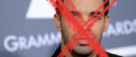 A close-up photo of Drake on the Grammy Awards red carpet. A red "X" has been drawn over his face.