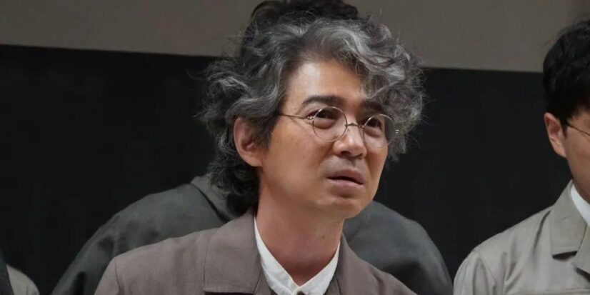 A slight man in spectacles, a real scientist-type, gazes worriedly into the distance in a still from Godzilla Minus One.