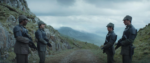 A screenshot from Andor, where four rebels stand on a dirt road under overcast skies, each wearing stolen imperial officer uniforms and looking sternly at each other