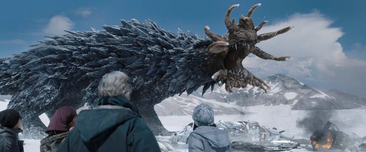Characters from Monarch: Legacy of Monsters watch as a monstrous kaiju emerges from a snowy landscape.